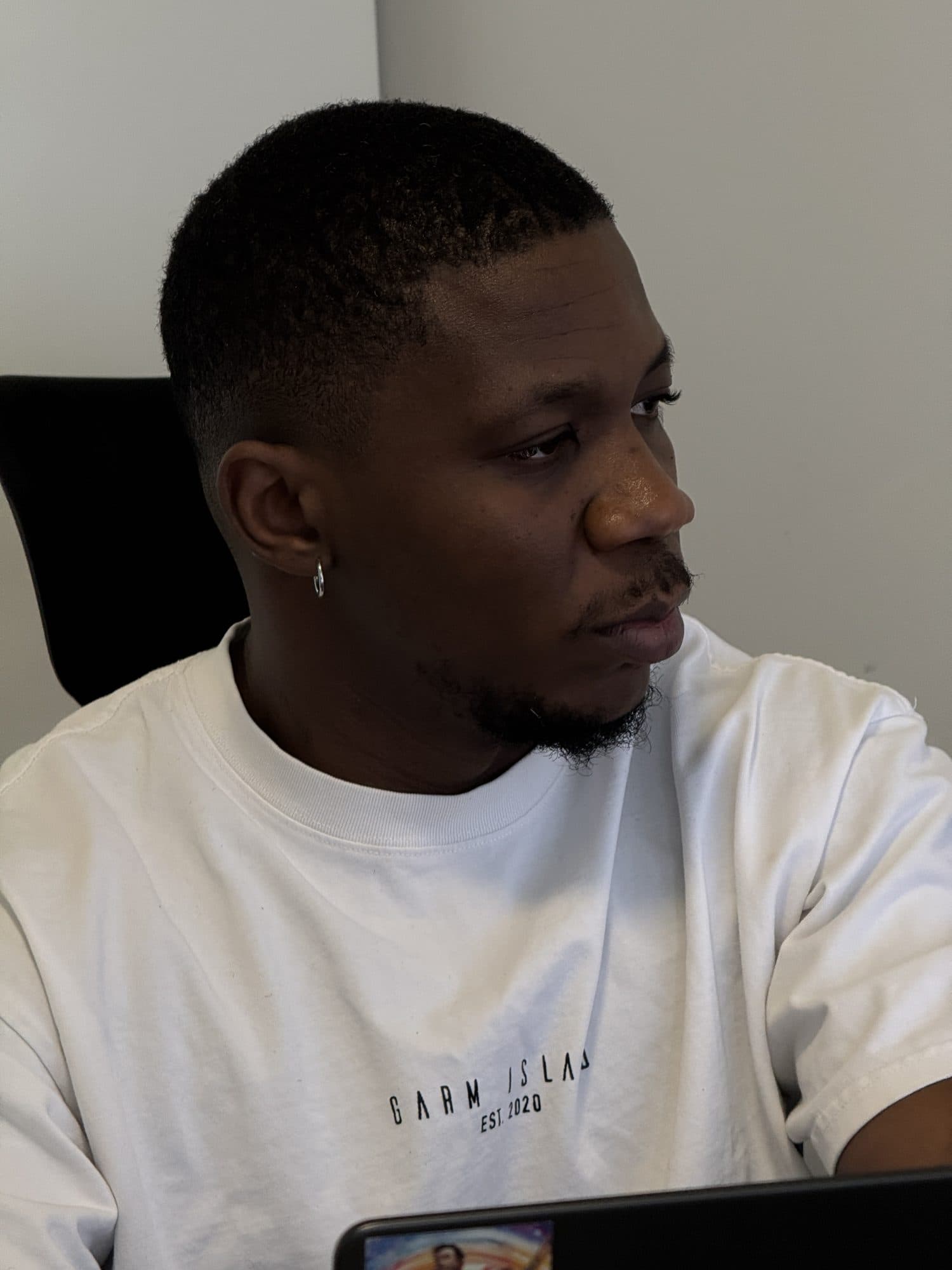 Femi in a white tee, focused on a laptop