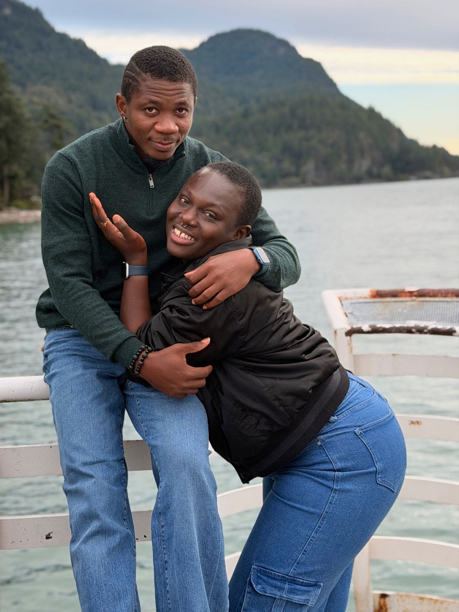 Leaning on a white railing over the water while she wraps both arms around me
