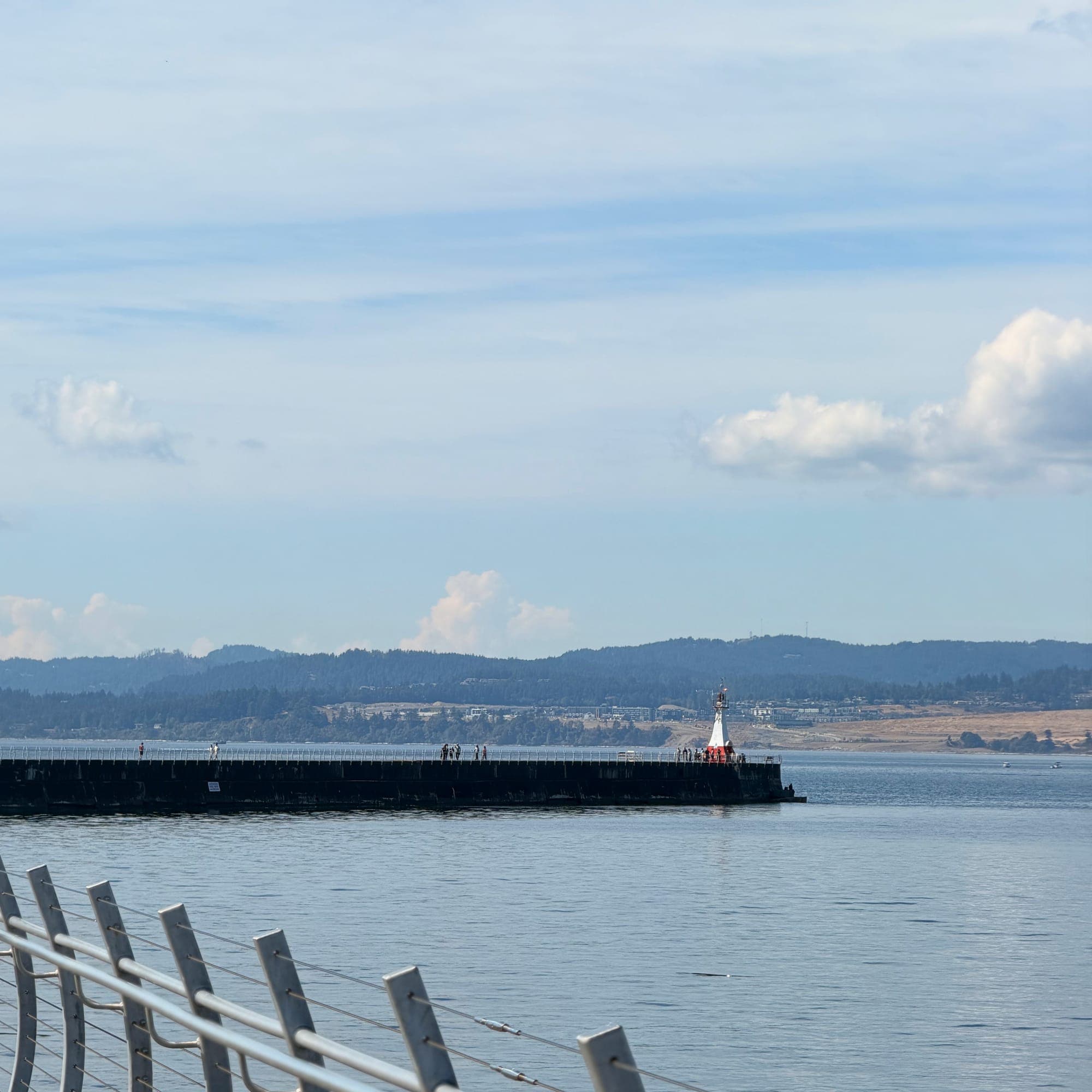 The breakwater curving out to a small lighthouse under a blue sky