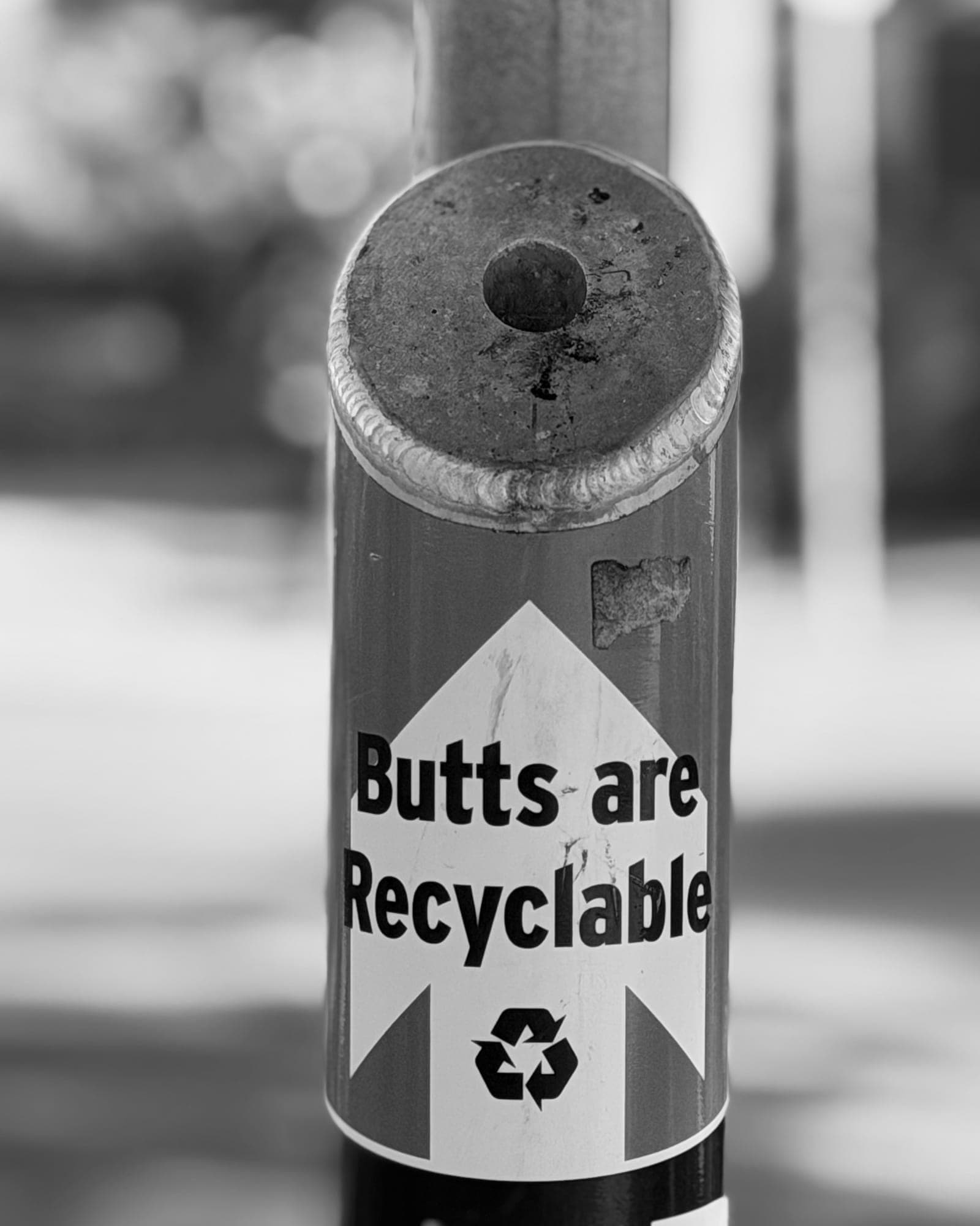 Close-up of a cigarette receptacle labelled Butts are Recyclable, in black and white