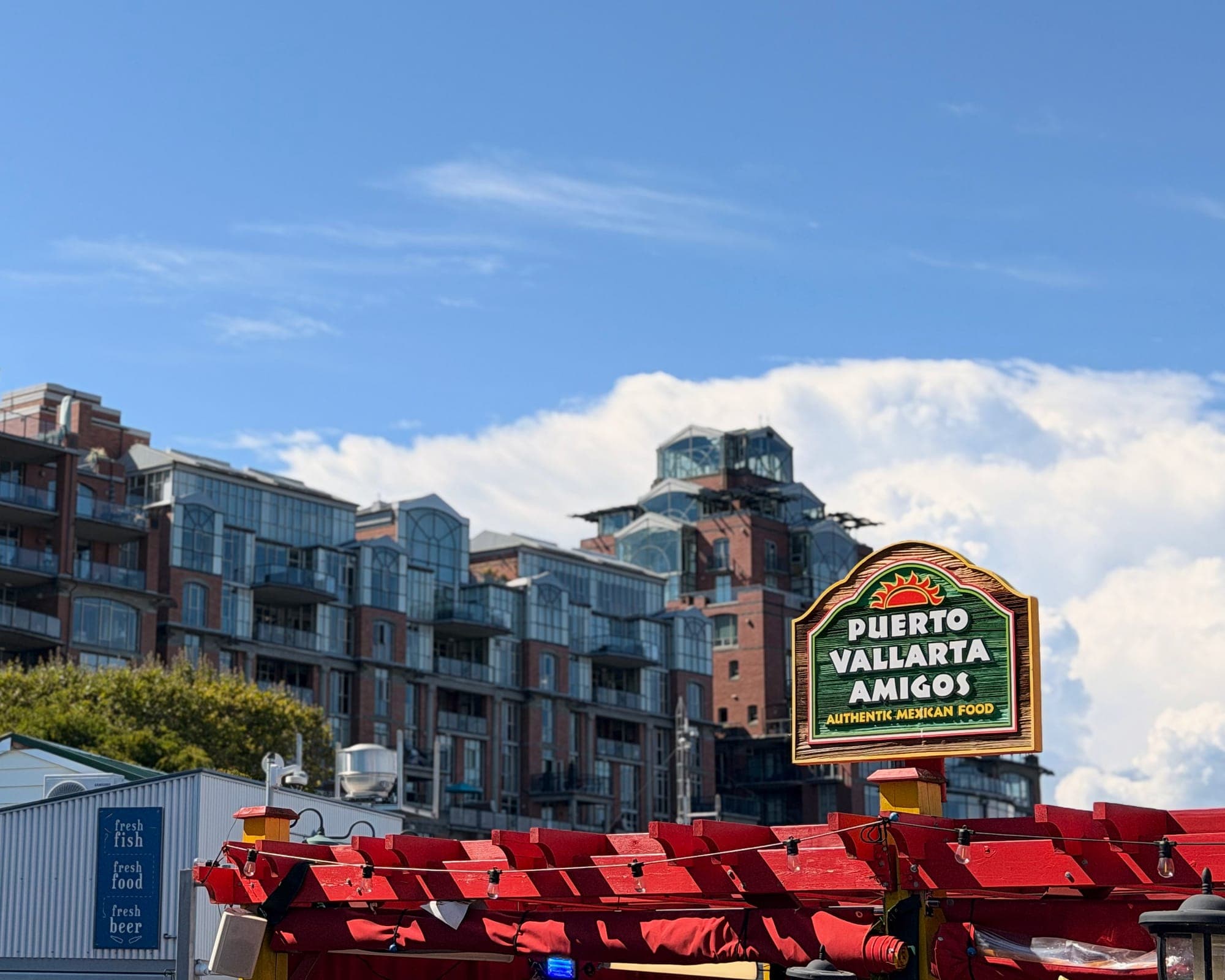 The Puerto Vallarta Amigos sign above a row of red patio umbrellas, condos behind